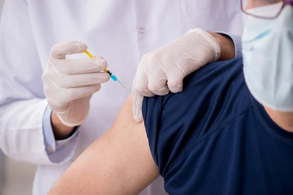 Gammal manlig patient besöker ung manlig läkare i vaccinationsgrupp — Stockfoto