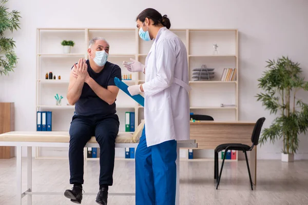 Old man visiting young doctor in covid-19 vaccination concept — Stock Photo, Image