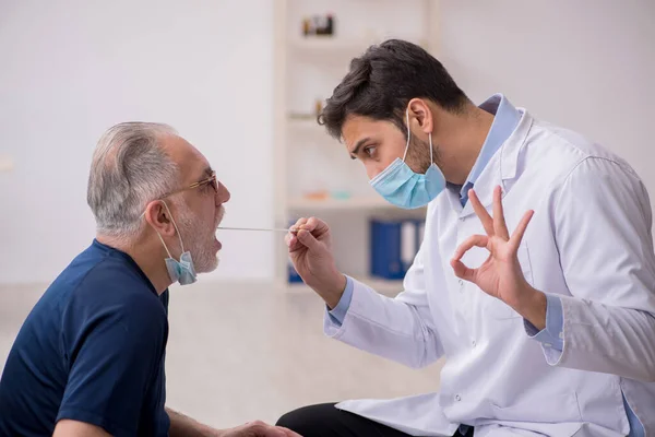 Yaşlı erkek hasta genç doktor otorhinolaryngologis 'i ziyaret ediyor. — Stok fotoğraf