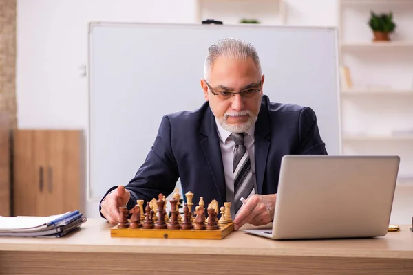 Viejo empleado jugando ajedrez en el lugar de trabajo — Foto de Stock
