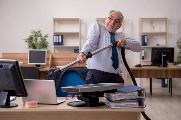 職場で掃除機を持っている古いビジネスマンの従業員 — ストック写真