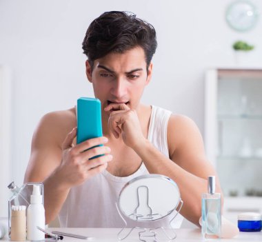 Genç yakışıklı adam aynaya bakıyor.