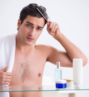 Genç adam banyoda çalışmak için hazırlanıyor.