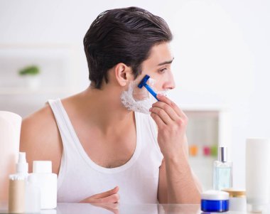 Genç yakışıklı adam sabah erkenden tıraş oluyor.