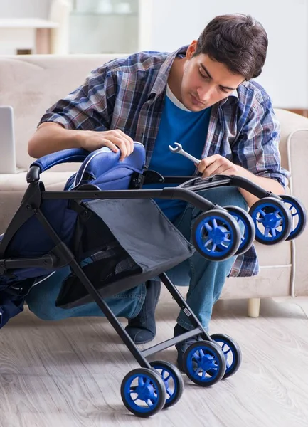 Young father assembling baby pram at home — Stock Photo, Image