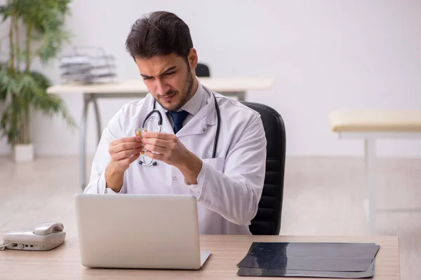 Giovane medico di sesso maschile in possesso di pillole in clinica — Foto Stock