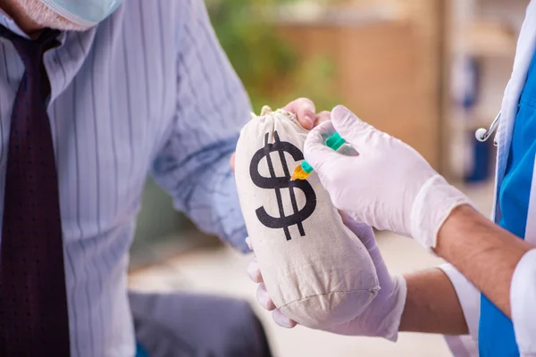 Young male doctor visiting old businessman at workplace — Stock Photo, Image