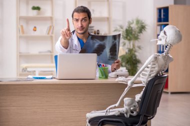 Genç doktor radyoloji uzmanı ve iskelet hastası klinikte.