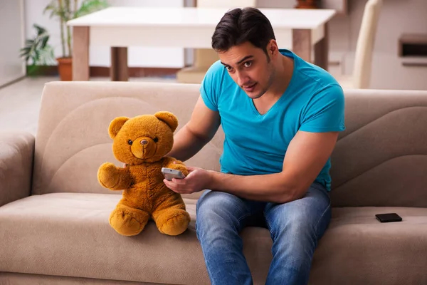 Jovem sentado com urso brinquedo em casa — Fotografia de Stock