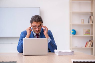 Genç erkek çalışan ofiste beyaz tahtanın önünde oturuyor.