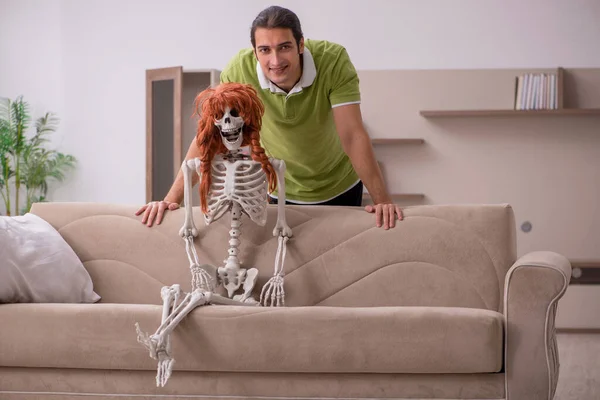 Jeune homme assis sur le canapé avec squelette féminin — Photo