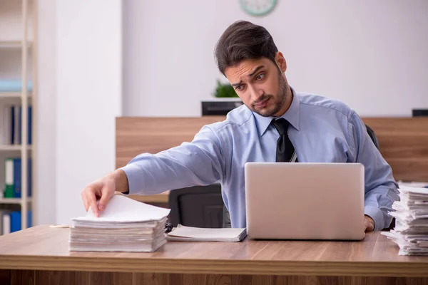 Joven empleado masculino y demasiado trabajo en la oficina —  Fotos de Stock