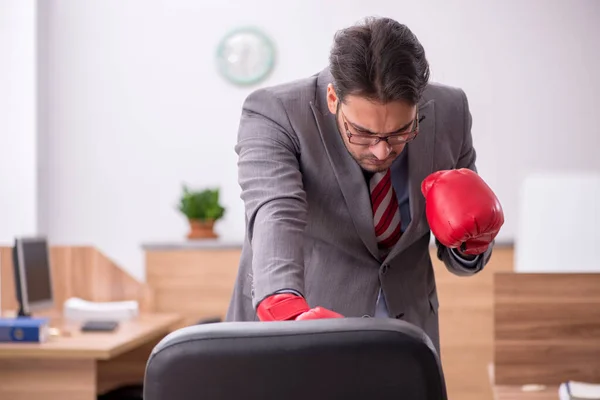 Ung man anställd bär boxningshandskar på arbetsplatsen — Stockfoto