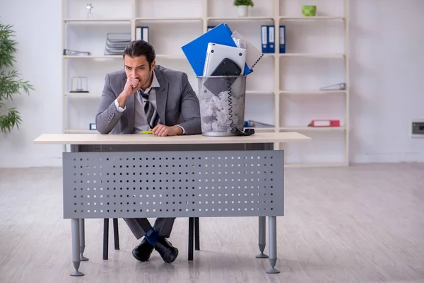 Fired young businessman with recycle bin in the office