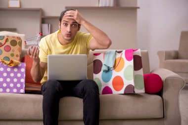 Evde bir sürü çantası olan genç bir adam var.