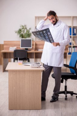 Genç erkek doktor radyoloji uzmanı ofiste oturuyor.