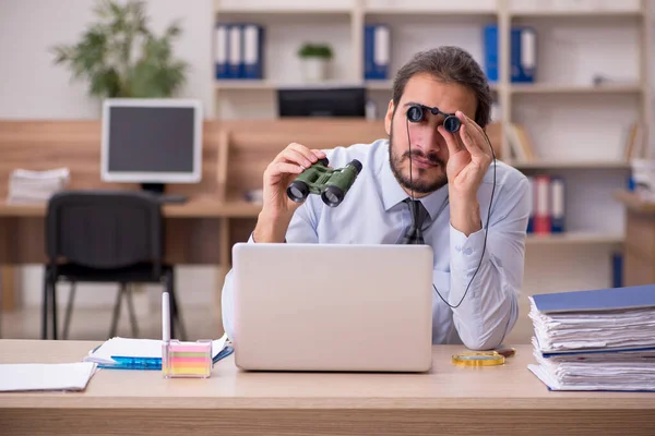 Joven empleado masculino sosteniendo prismáticos en espionaje industrial c — Foto de Stock