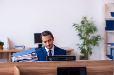 Ofisteki aşırı işten memnun olmayan genç bir erkek işçi.