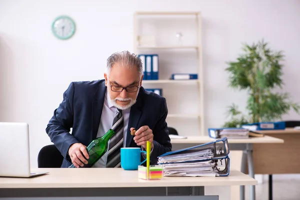 Un vieil employé boit de l'alcool au bureau — Photo