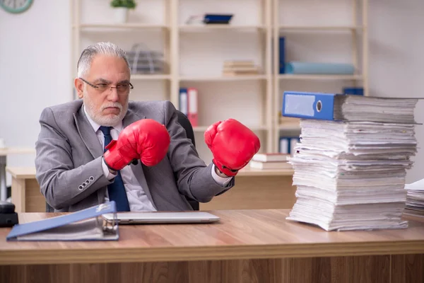 職場でボクシンググローブを身に着けている古いビジネスマンの従業員 — ストック写真