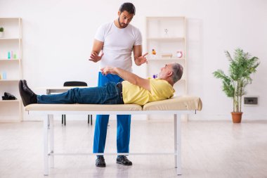 Yaşlı erkek hasta, genç erkek doktor masörünü ziyaret ediyor.
