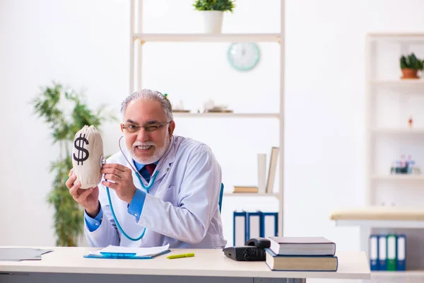 Yaşlı doktor hastanede para çantasını tutuyor. — Stok fotoğraf