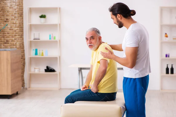 Paciente varón viejo que visita al quiropráctico joven del doctor masculino — Foto de Stock