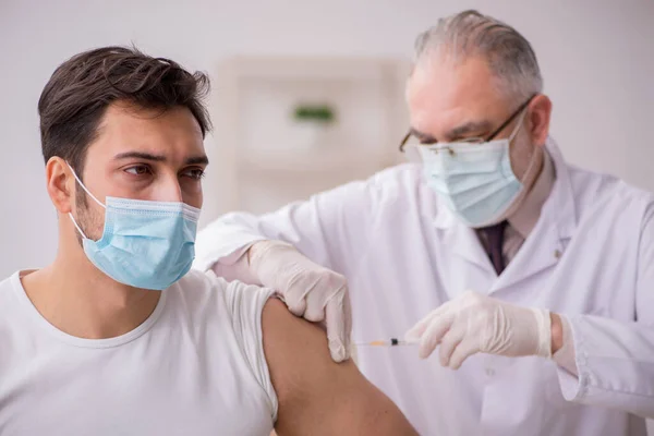 Junge männliche Patientin besucht alten Arzt im Impfpass — Stockfoto