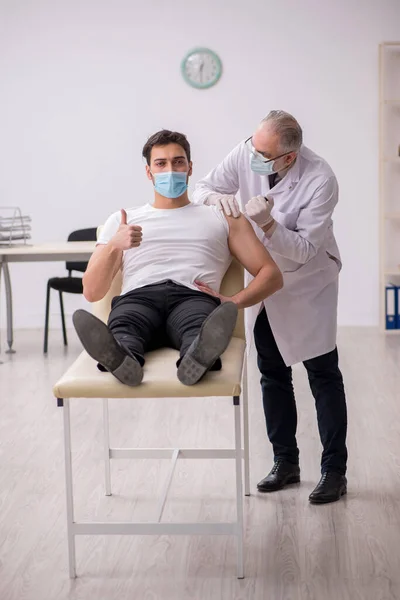 Junge männliche Patientin besucht alten Arzt im Impfpass — Stockfoto