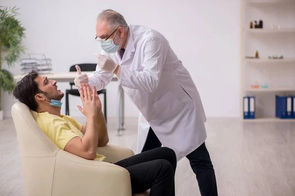 Junge männliche Patienten besuchen alte männliche Arzt HNO-Arzt — Stockfoto