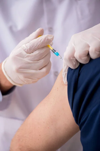 Gammal manlig patient besöker ung manlig läkare i vaccinationsgrupp — Stockfoto