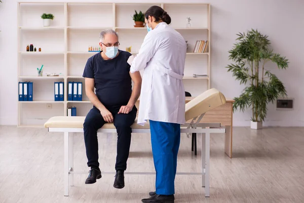 Vecchio visita giovane medico in covid-19 concetto di vaccinazione — Foto Stock