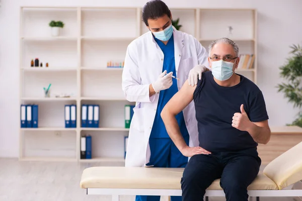 Starý muž navštíví mladého lékaře v konceptu covid-19 vakcinace — Stock fotografie