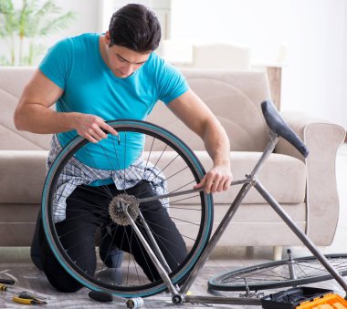 Evde bisiklet tamir eden genç bir adam.