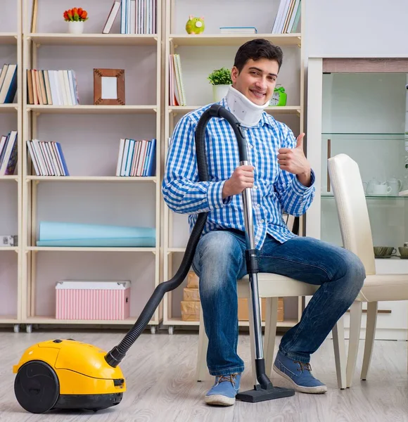 Injured man with neck injury vacuum cleaning house — Stock Photo, Image