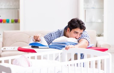 Genç baba yeni doğan bebeğe bakıyor.