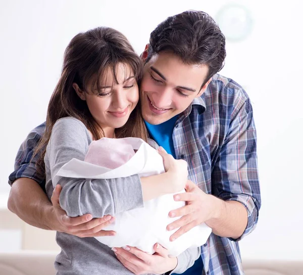 Unga föräldrar med sitt nyfödda barn nära sängen barnsäng — Stockfoto