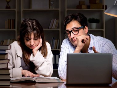 İki öğrenci geç saatlere kadar çalışıp sınavlara hazırlanıyor.