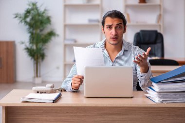 Genç erkek çalışan ofiste oturuyor.