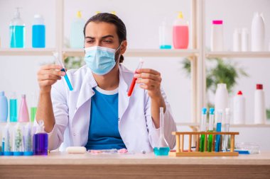 Genç erkek kimyager laboratuarda sabun test ediyor.