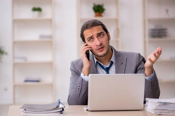 Giovane dipendente maschio infelice con un lavoro eccessivo in ufficio — Foto Stock