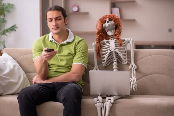 Jeune homme assis sur le canapé avec squelette féminin — Photo