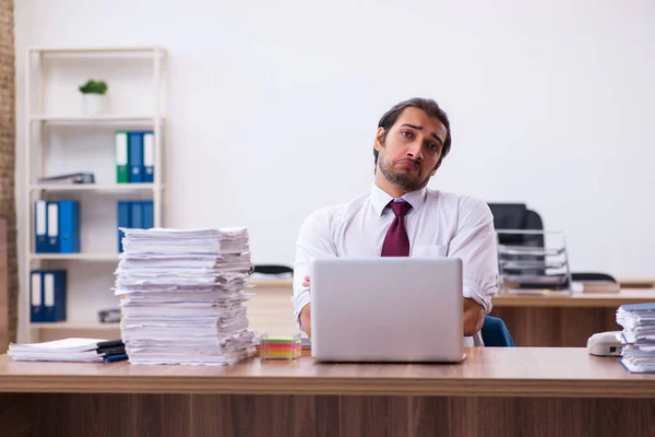 Молодой работник мужчина недоволен чрезмерной работой в офисе — стоковое фото