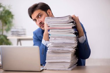 Genç bir erkek çalışan ve ofiste çok fazla iş var.