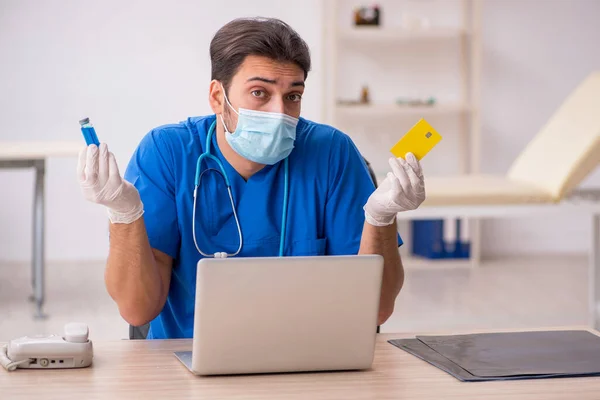 Jovem médico segurando cartão de crédito durante pandemia — Fotografia de Stock