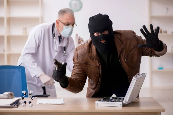 Homem mascarado ladrão roubando vacina do velho médico — Fotografia de Stock