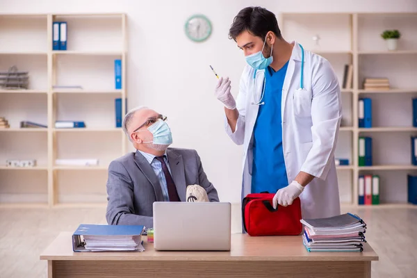 Un tânăr doctor vizitează un bătrân om de afaceri la locul de muncă — Fotografie, imagine de stoc