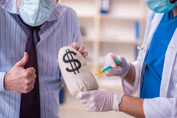 Young male doctor visiting old businessman at workplace — Stock Photo, Image