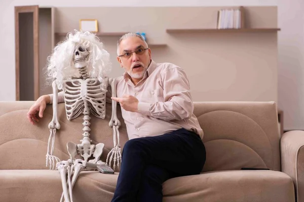 Alter Mann sitzt auf dem Sofa mit dem weiblichen Skelett — Stockfoto