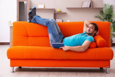 Genç erkek öğrenci turuncu koltukta oturuyor.